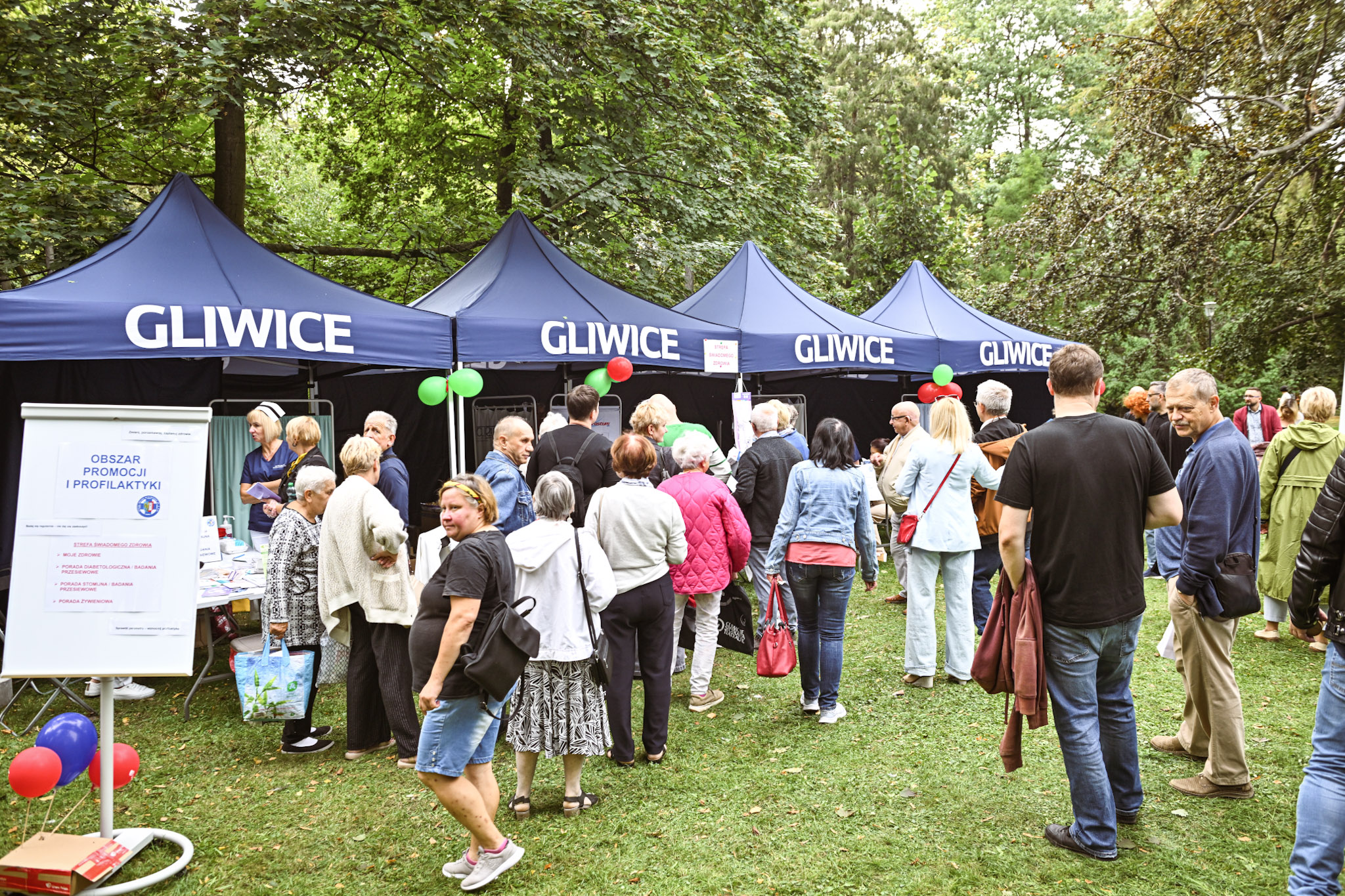 Fot. M.Buksa/UM Gliwice ludzie na trawniku w parku, przy namiotach z atrakcjami