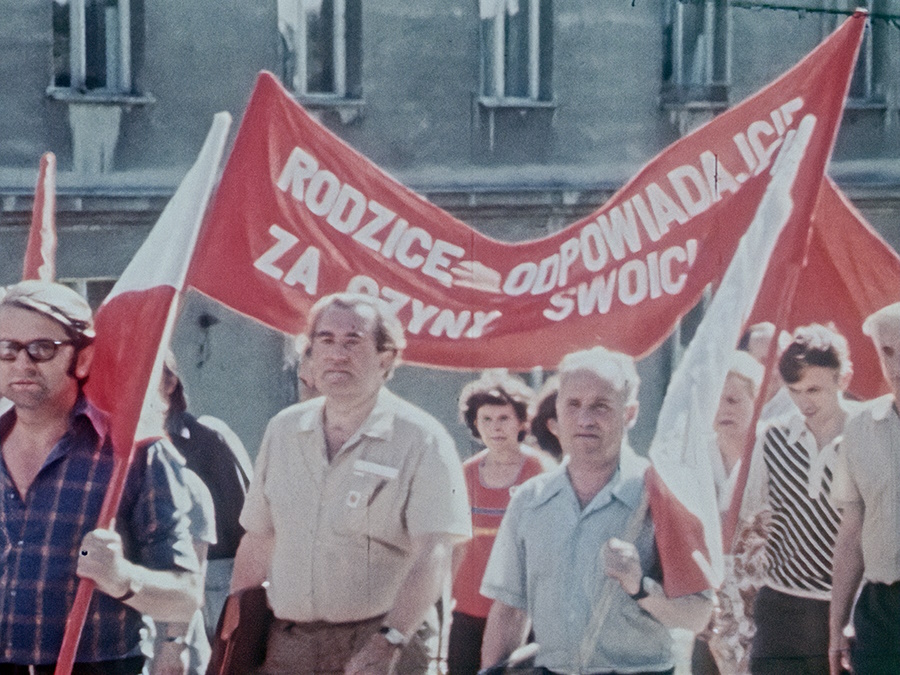 Ludzie idący z flagami i banerem