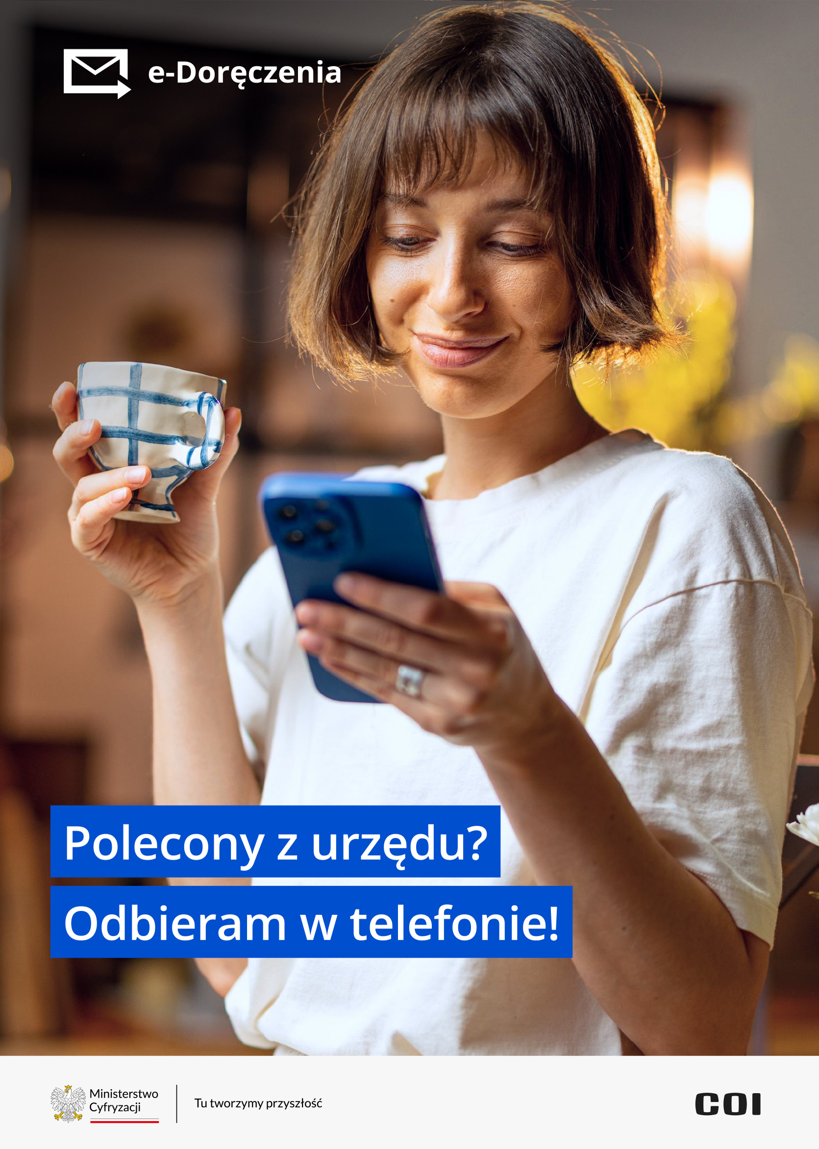 kobieta wpatrzona w ekran telefonu i trzymająca kubek w drugiej ręce