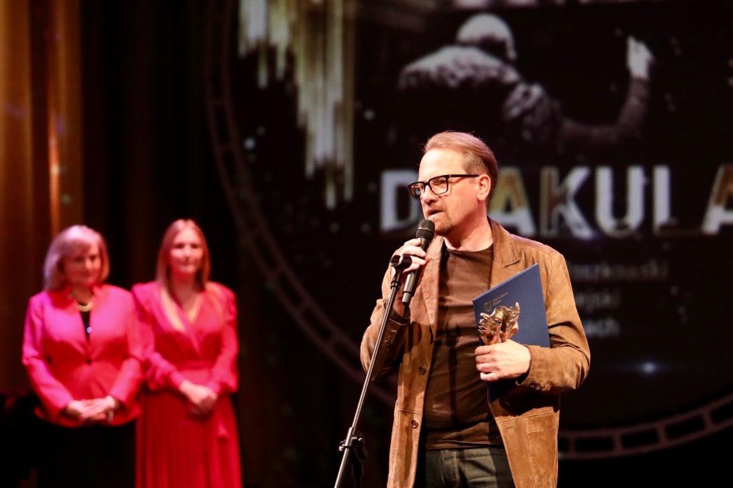 Mężczyzna ze statuetką przy mikrofonie