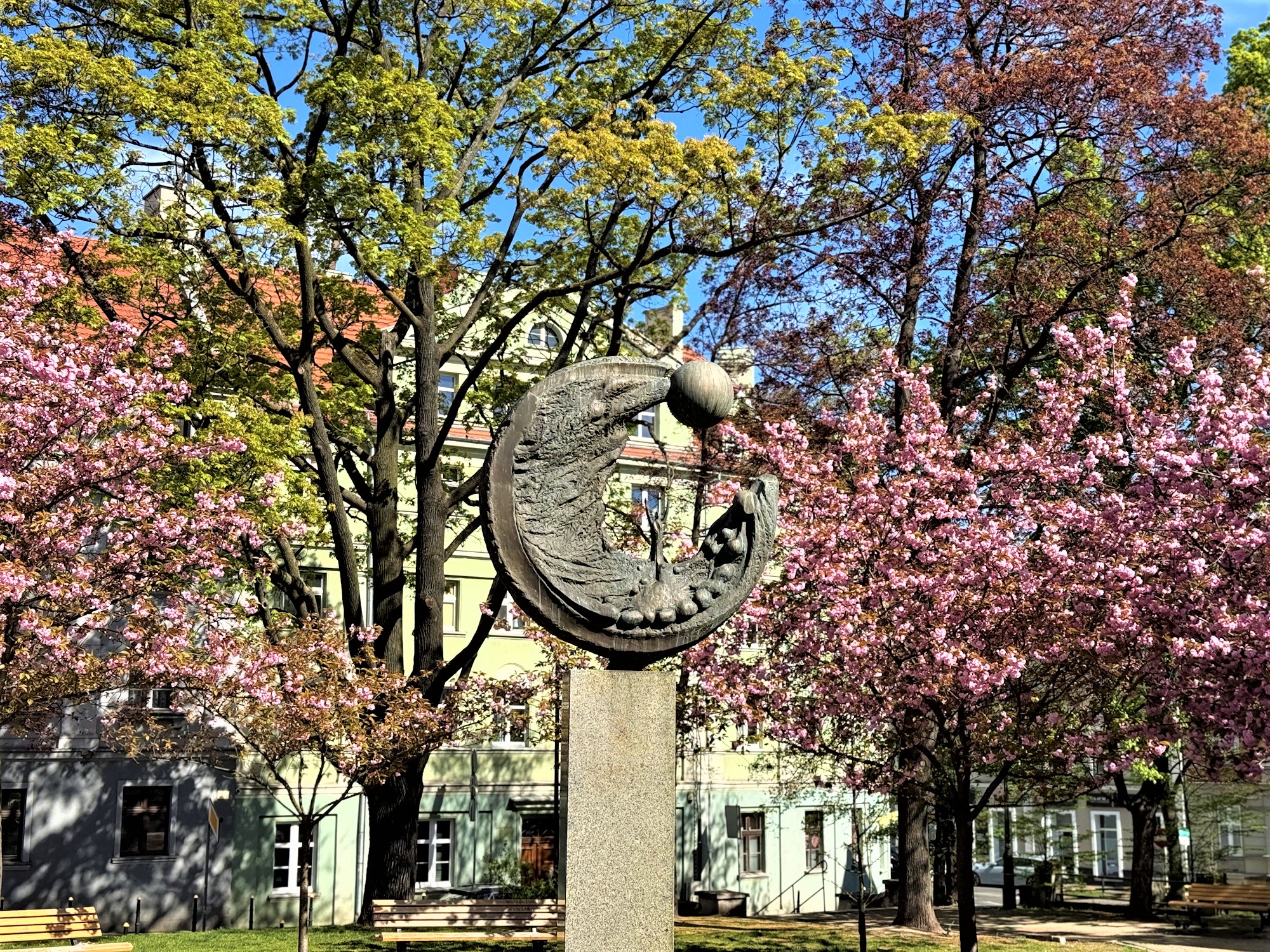 Rzeźba wśród drzew z różowymi kwiatkami