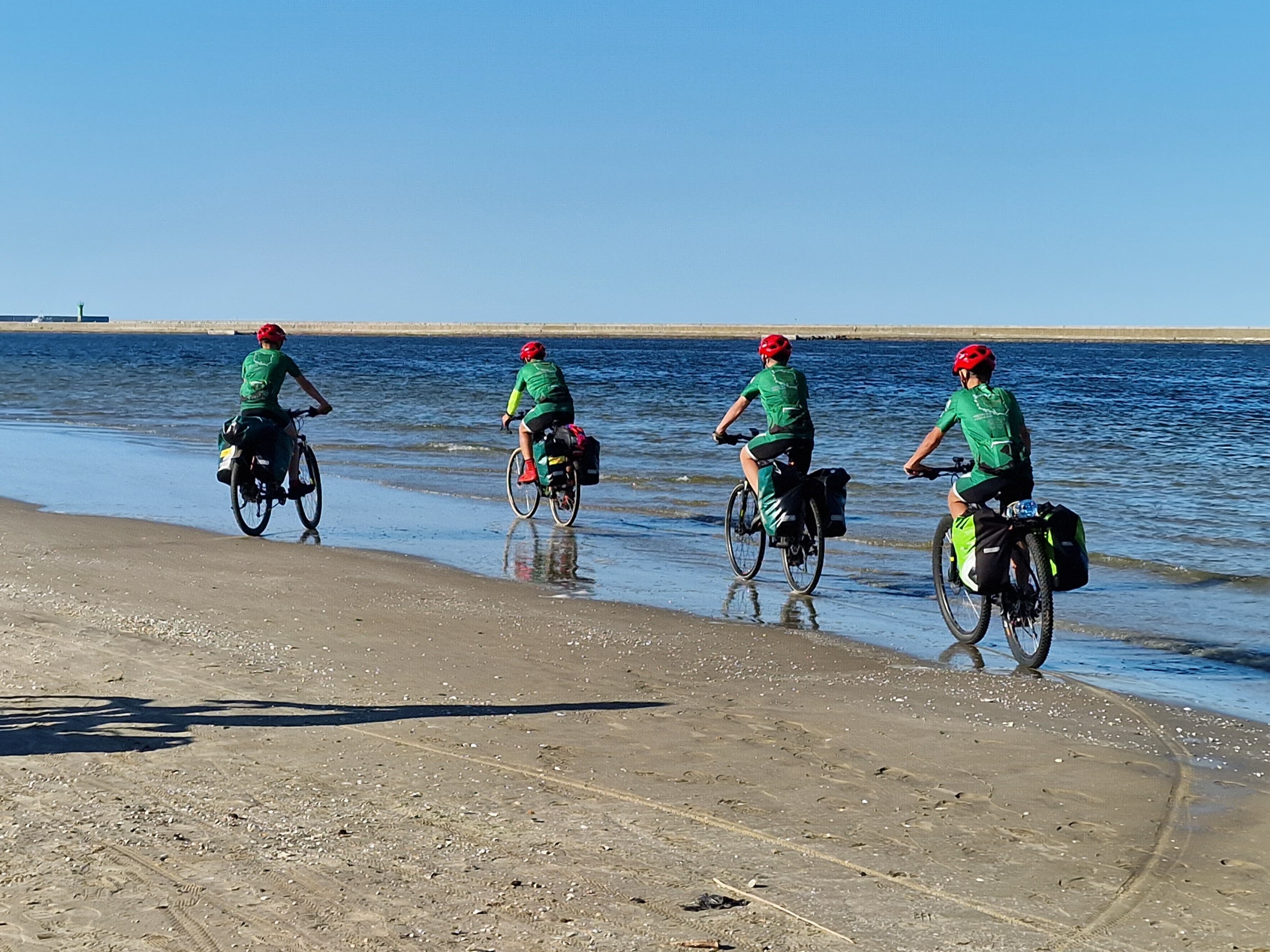 rowerzyści jadą linia brzegową morza