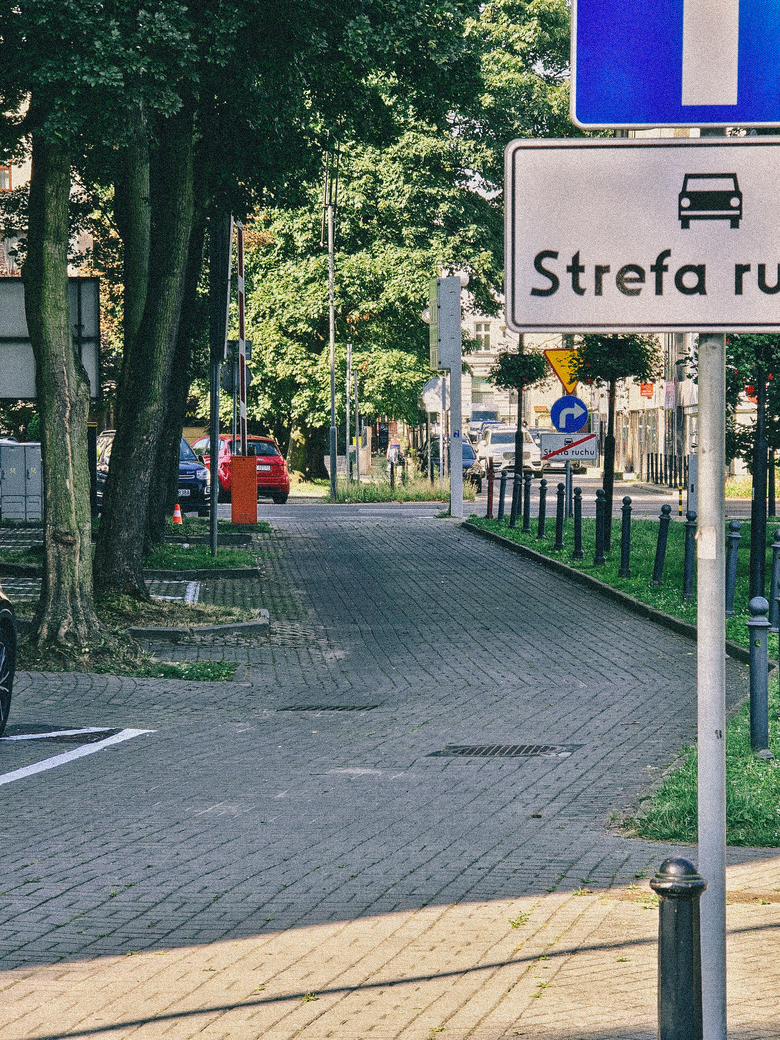 Fragment drogi za urzędem miejskim i znak "strefa ruchu"