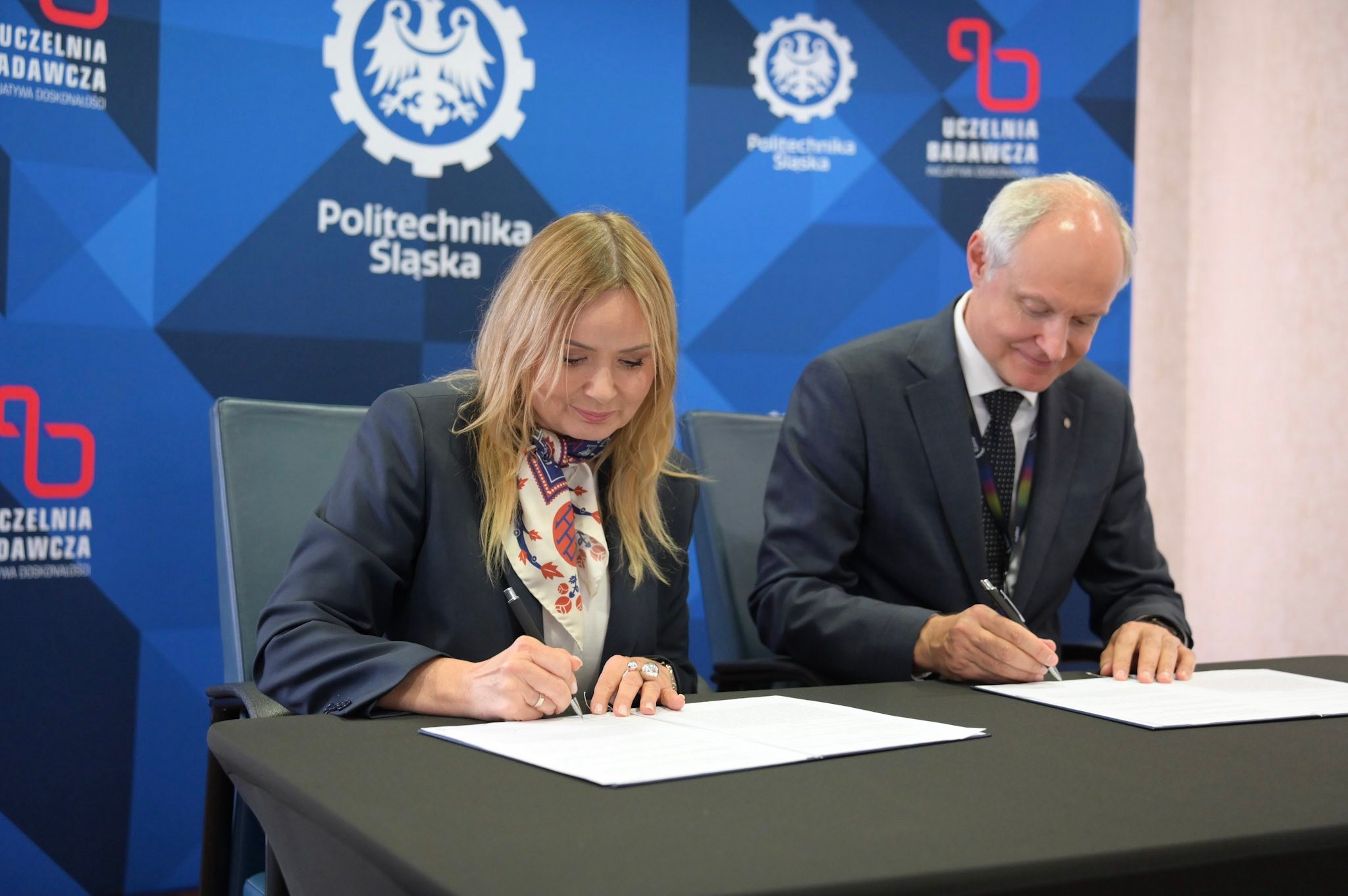 rektor i prezydent siedzą przy stole i podpisują dokumenty