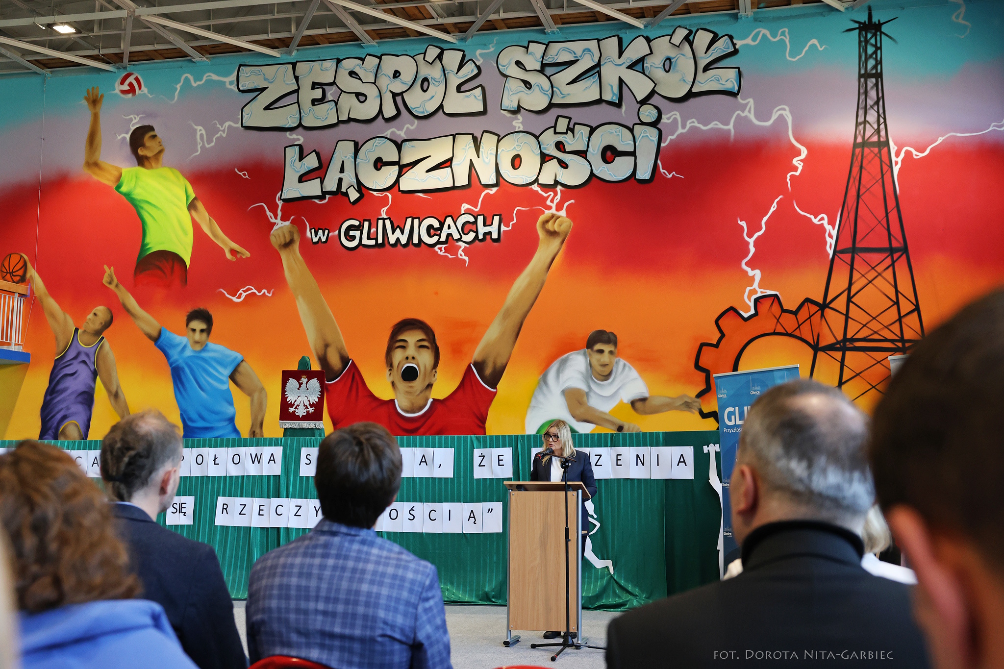 prezydent za mównicą na =tle grafiki