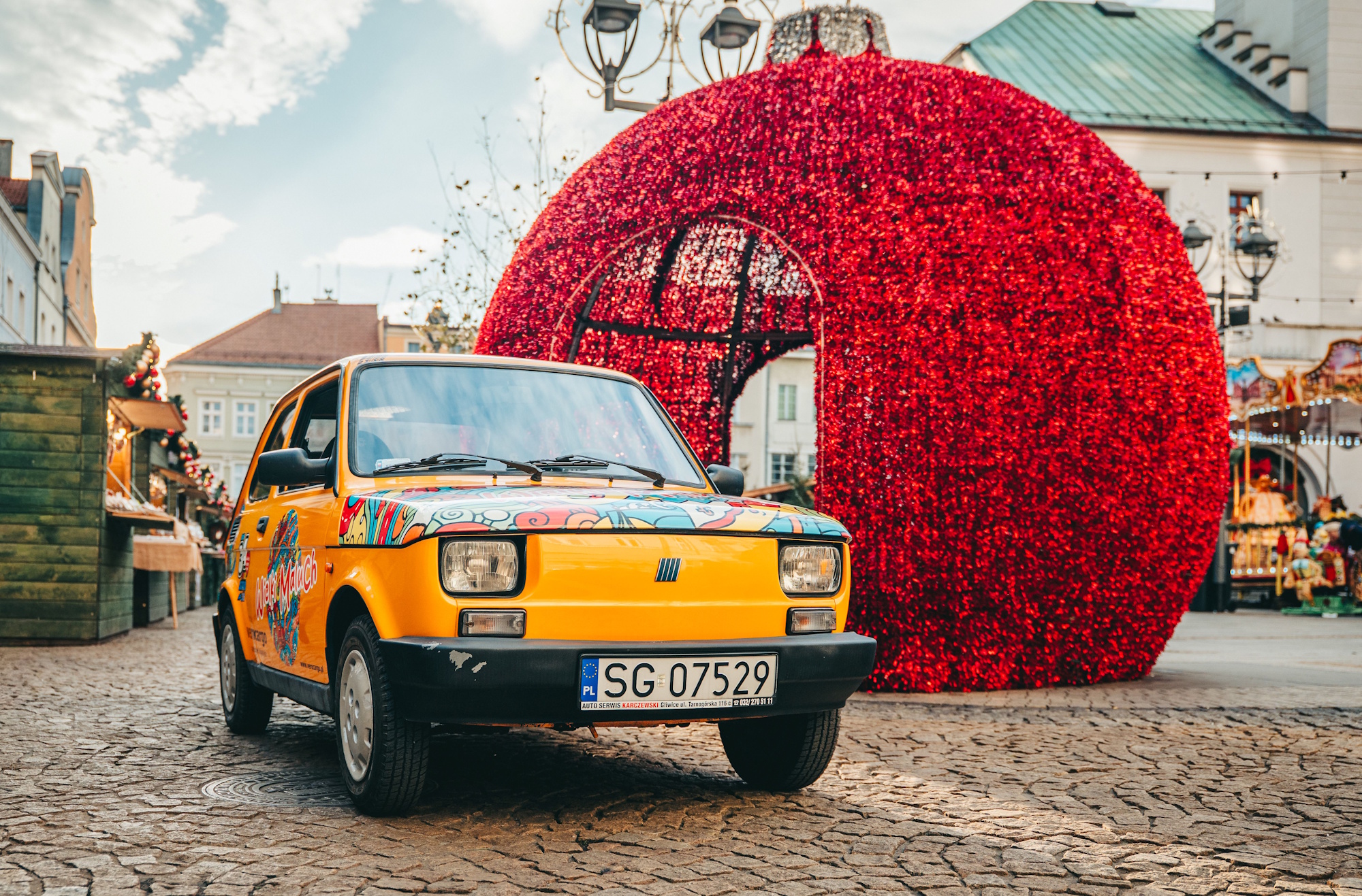 Żółty Fiat 126p przy ozdobnej bombce na gliwickim Rynku