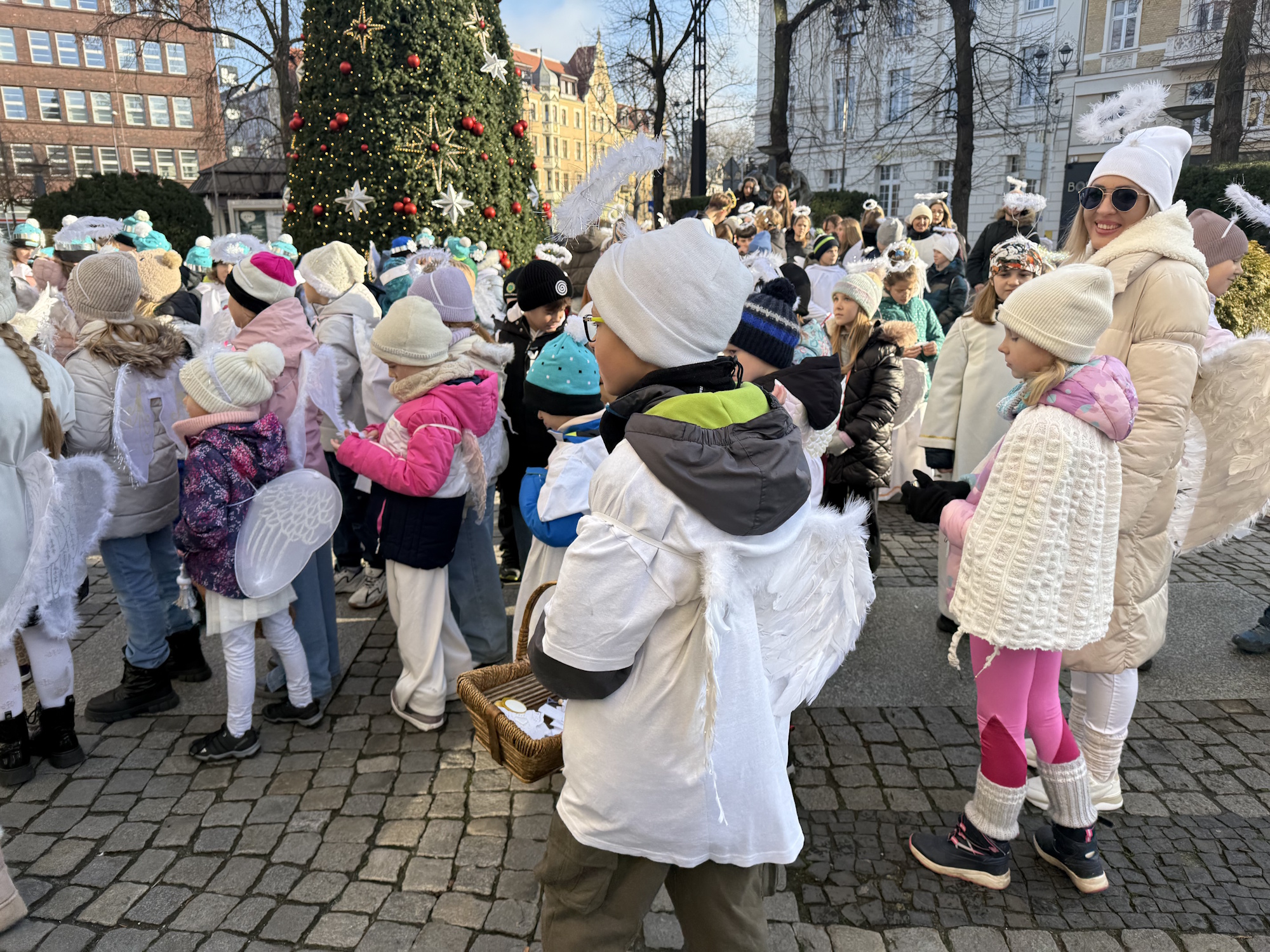 dzieci ze skrzydełkami przed urzędem
