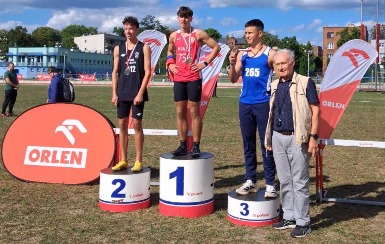 trzech chłopców na podium, obok mężczyzna