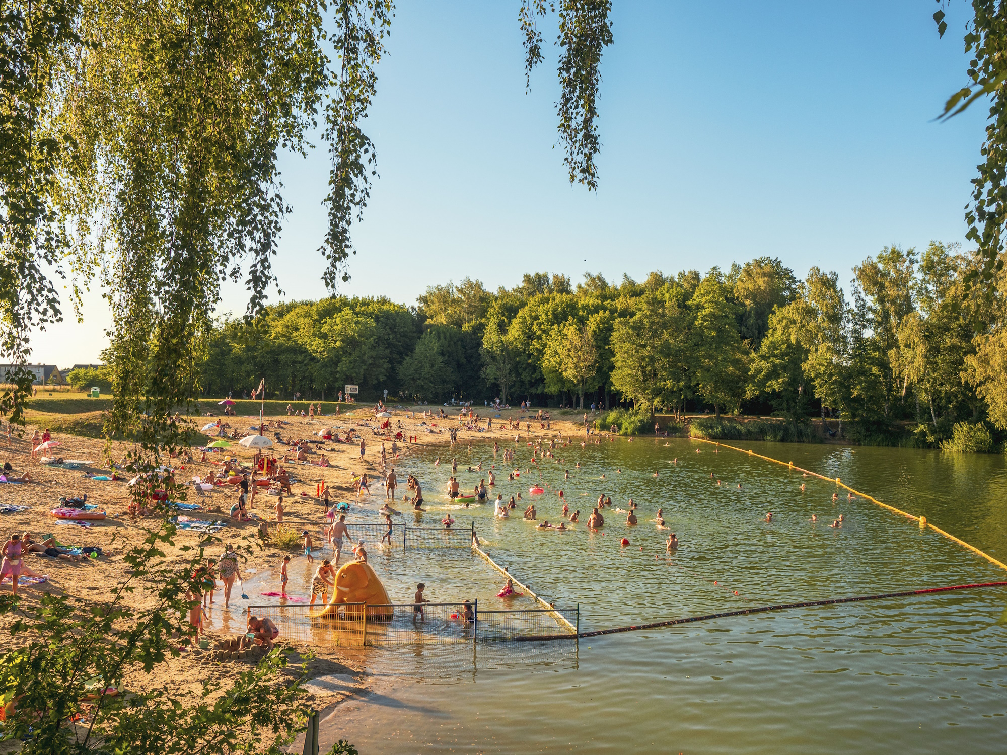 ludzie na plaży i fragment jeziora