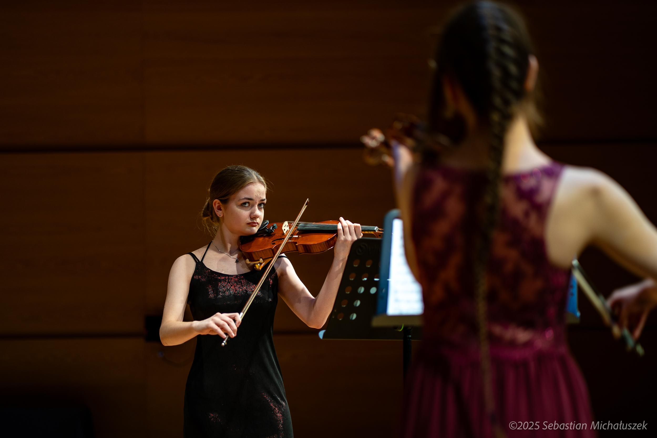 dwie skrzypaczki, jedna stoi tyłem