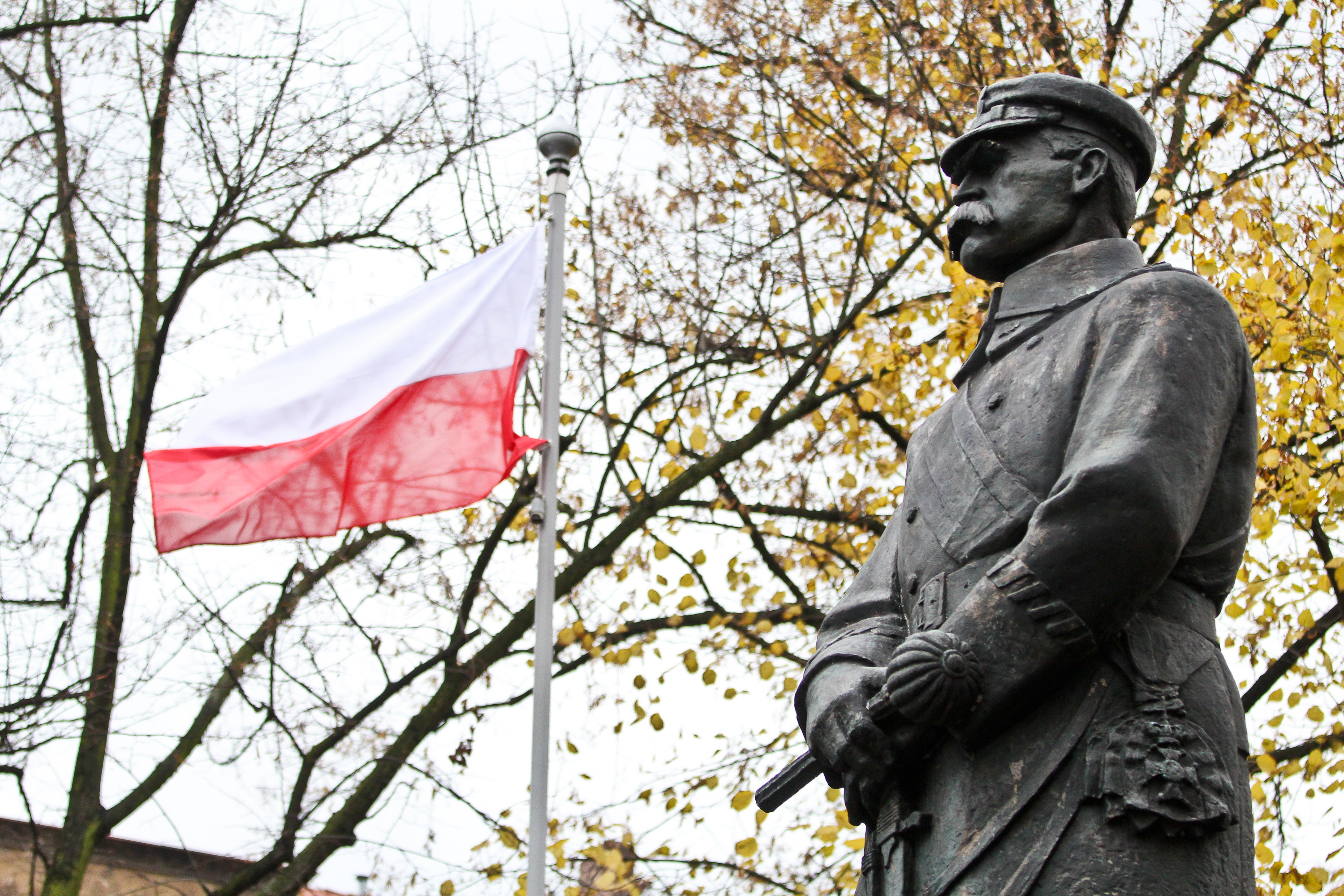 pomnik Piłsudskiego z powiewającą flagą Polski