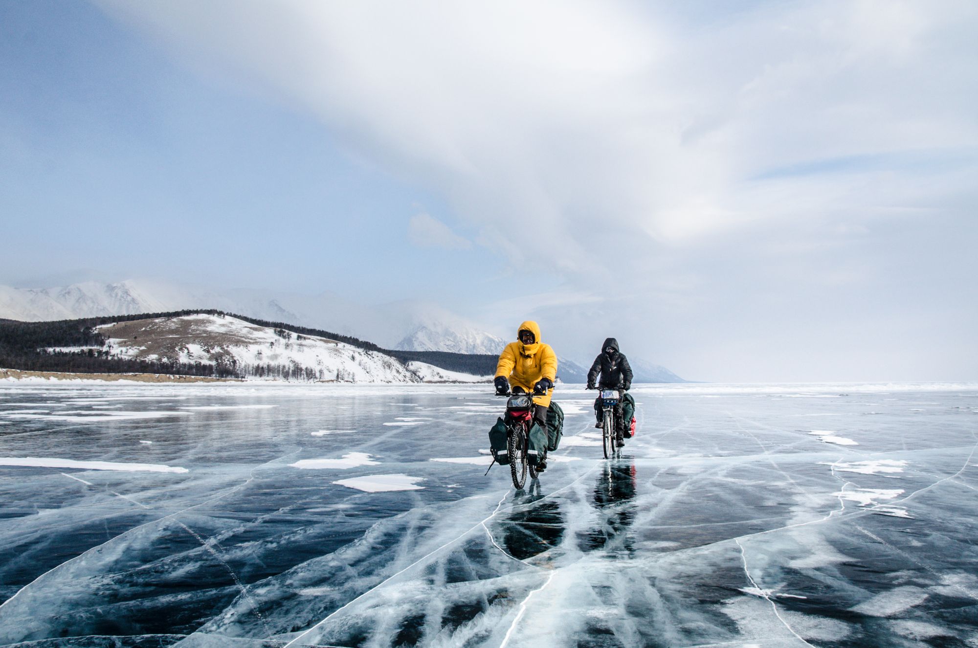 mężczyźni jadą rowerami przez jezioro Bajkał