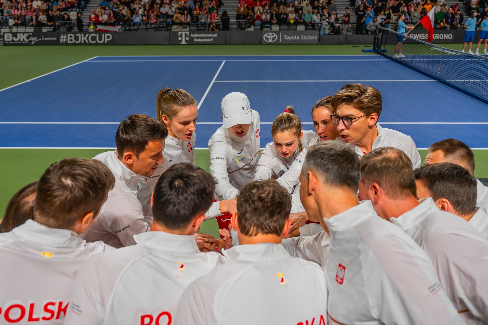 tenisiści i tenisistki przybijają sobie piątkę na korcie