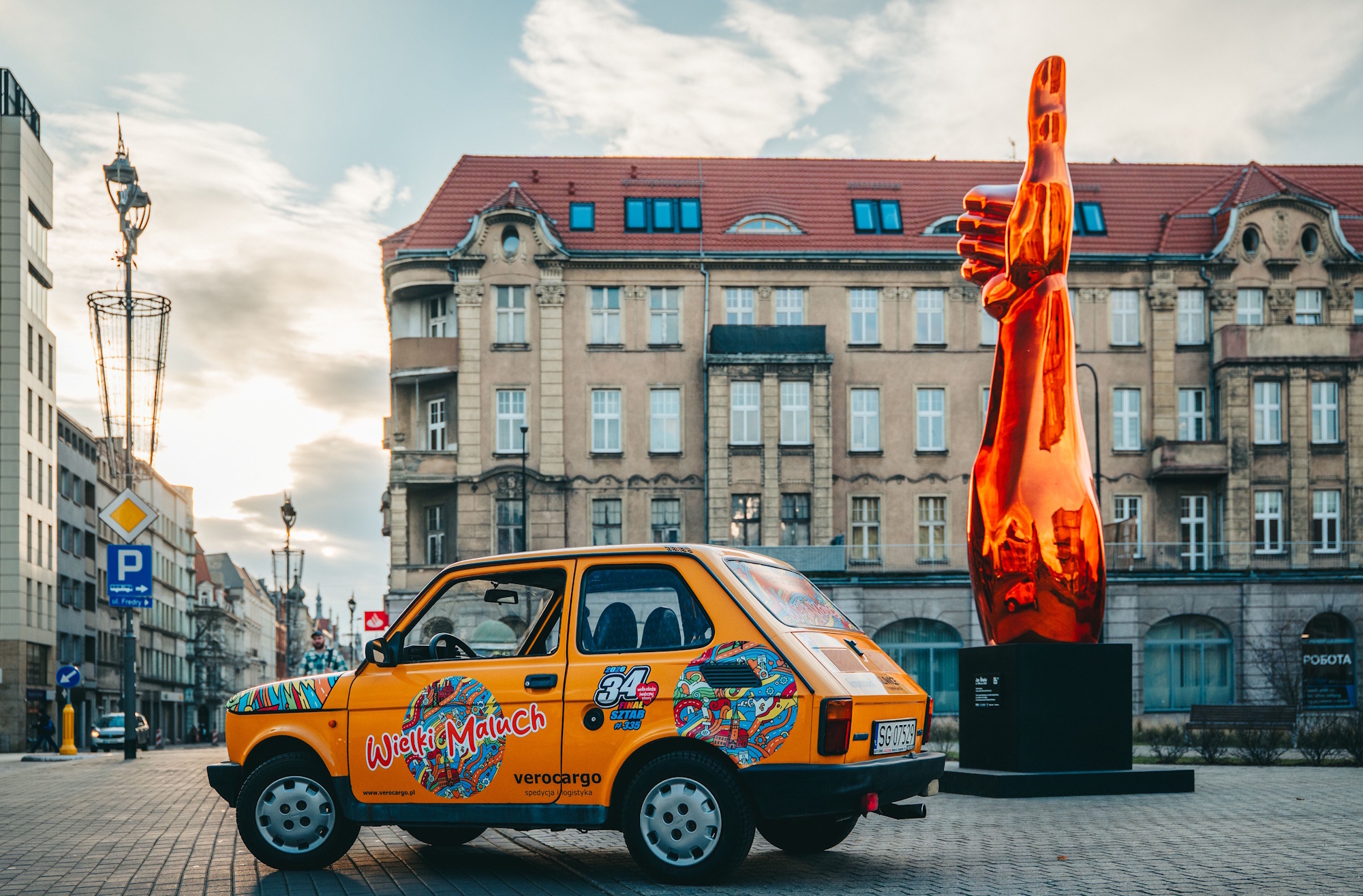 Żółty Fiat 126p przy rzeźbie kciuka w Gliwicach