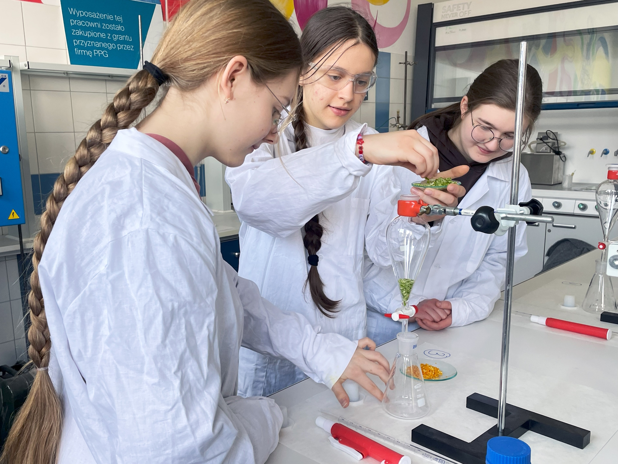 dziewczyny w białych fartuchach wykonują doświadczenie