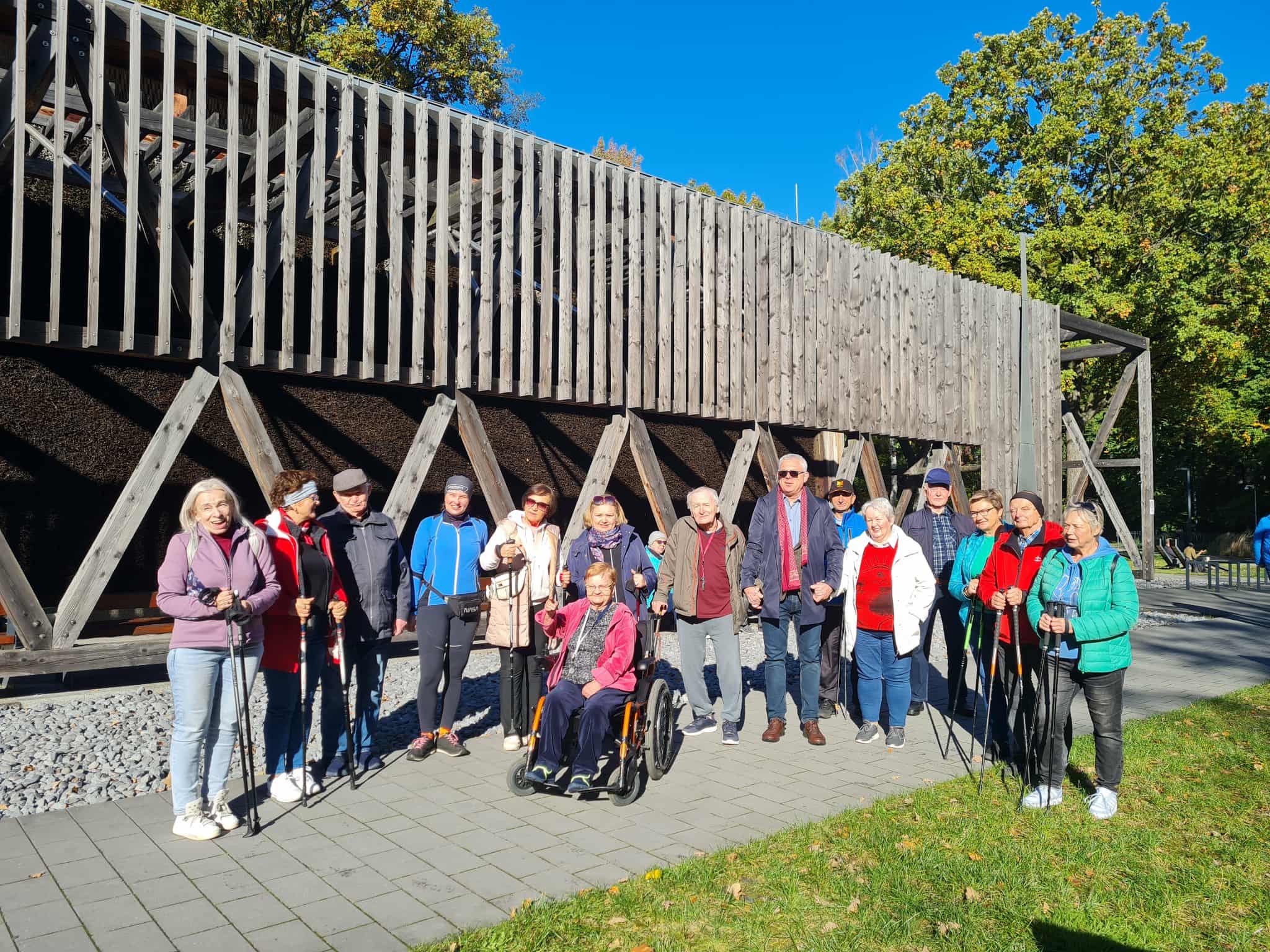 Seniorzy na spacerze nordic walking przed tężnią solankową