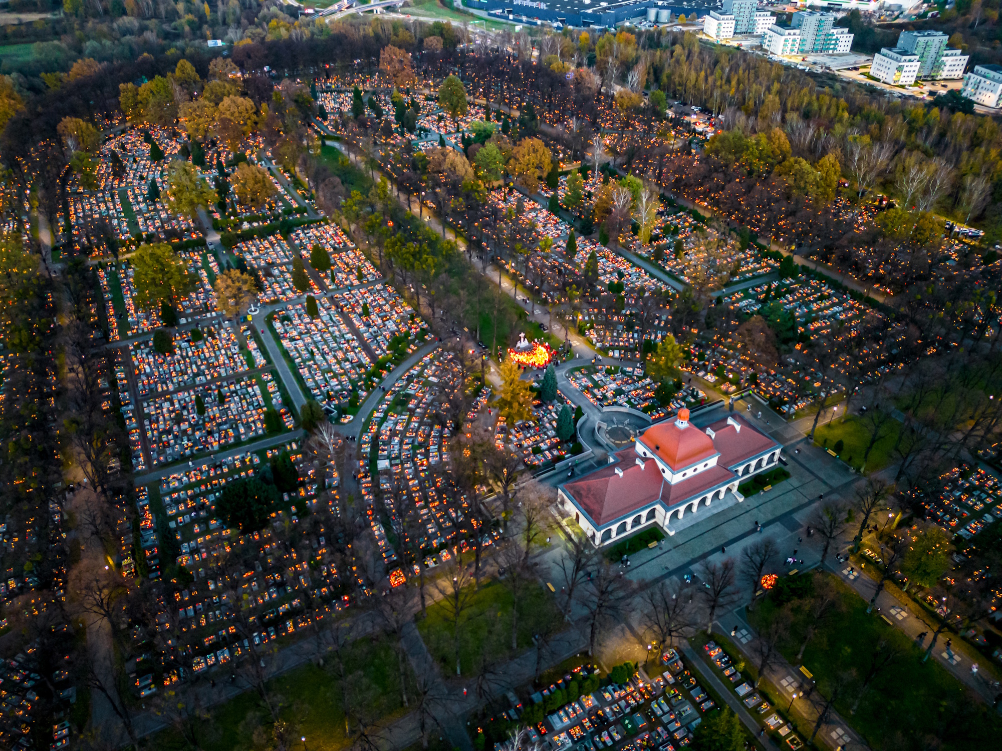 Cmentarz wieczorową porą z zapalonymi zniczami. Ujęcie z góry