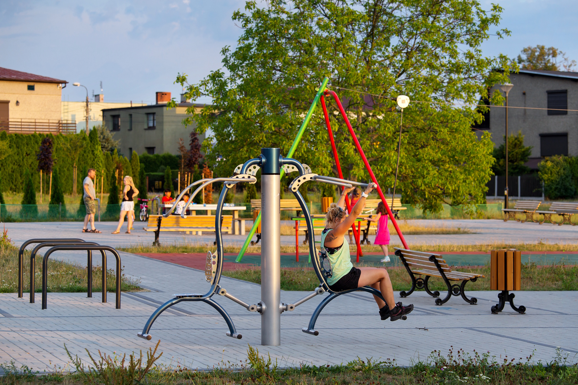 kobieta na siłowni plenerowej, w tle ławki