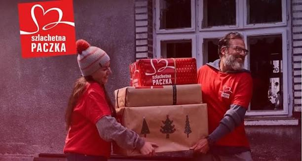 kobieta i mężczyzna ubrani w czerwone swetry niosą paczki